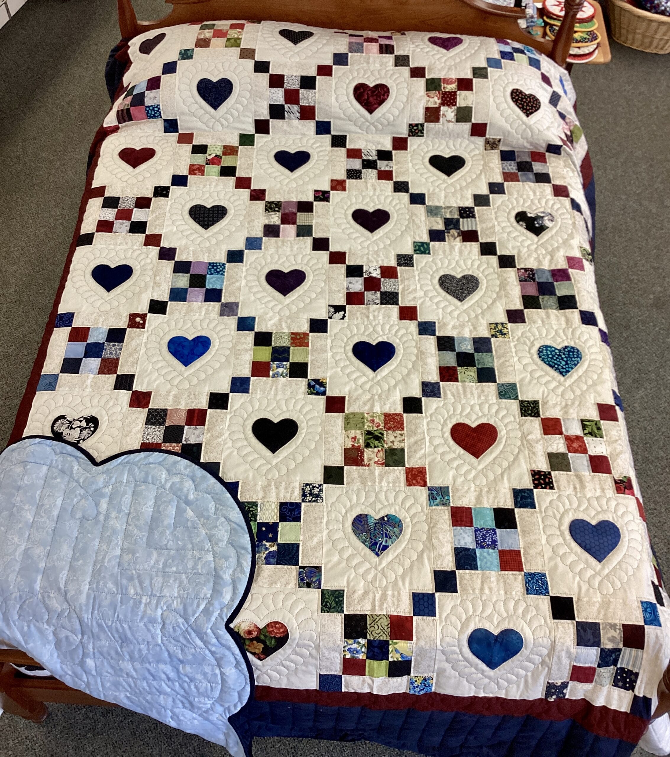 Handmade Amish 9 Patch Hearts quilt in Queen size featuring colorful pieced blocks, appliqué hearts, detailed hand stitching, and blue scalloped border from Lancaster County