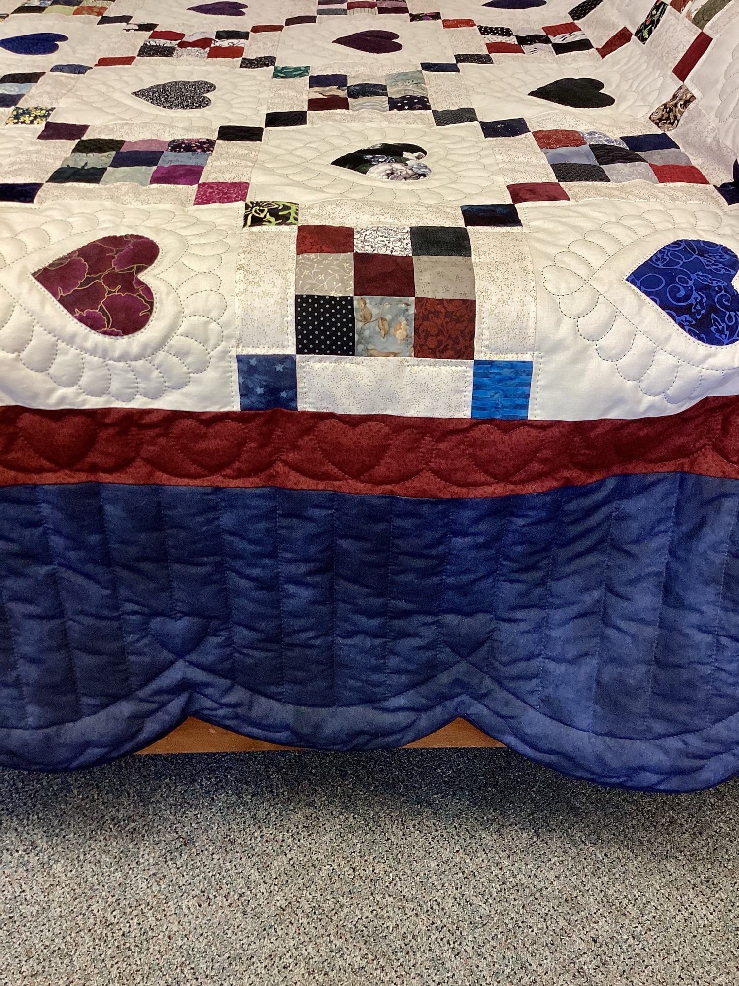 Handmade Amish 9 Patch Hearts quilt in Queen size featuring colorful pieced blocks, appliqué hearts, detailed hand stitching, and blue scalloped border from Lancaster County