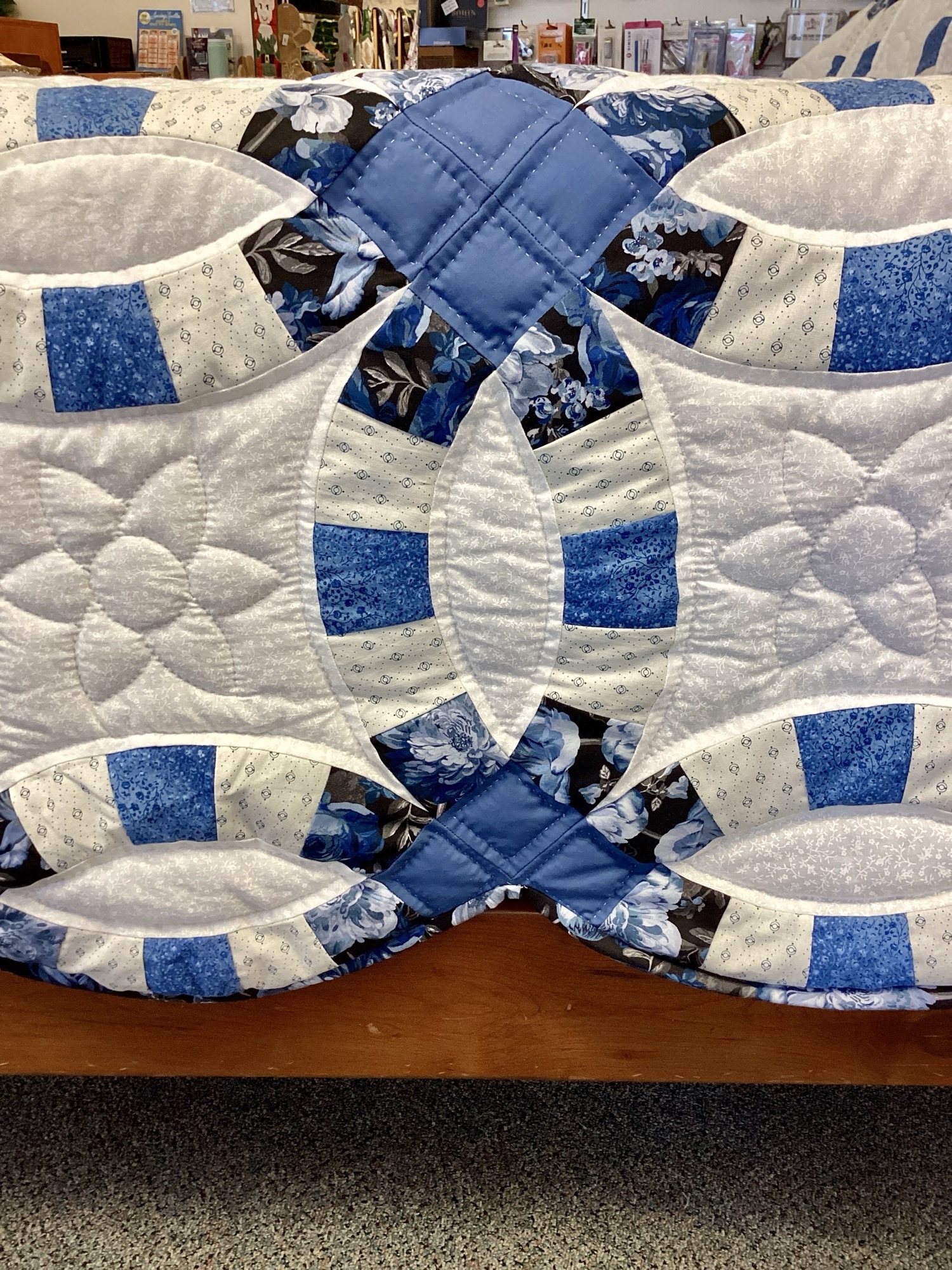 Hand-stitched blue Double Wedding Ring quilt with floral fabrics and white background