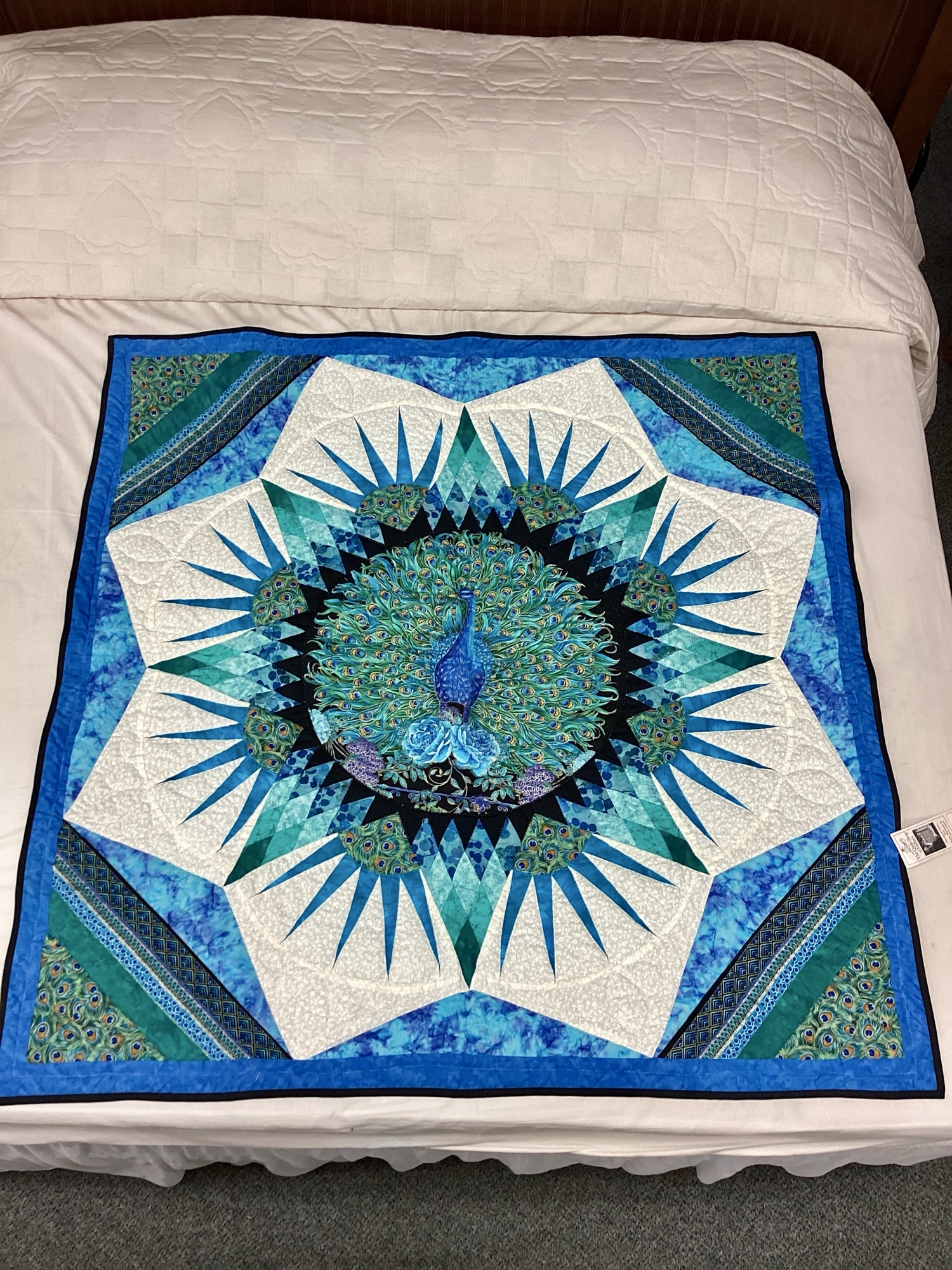 Hand-stitched peacock wall hanging featuring batik and peacock feather fabrics