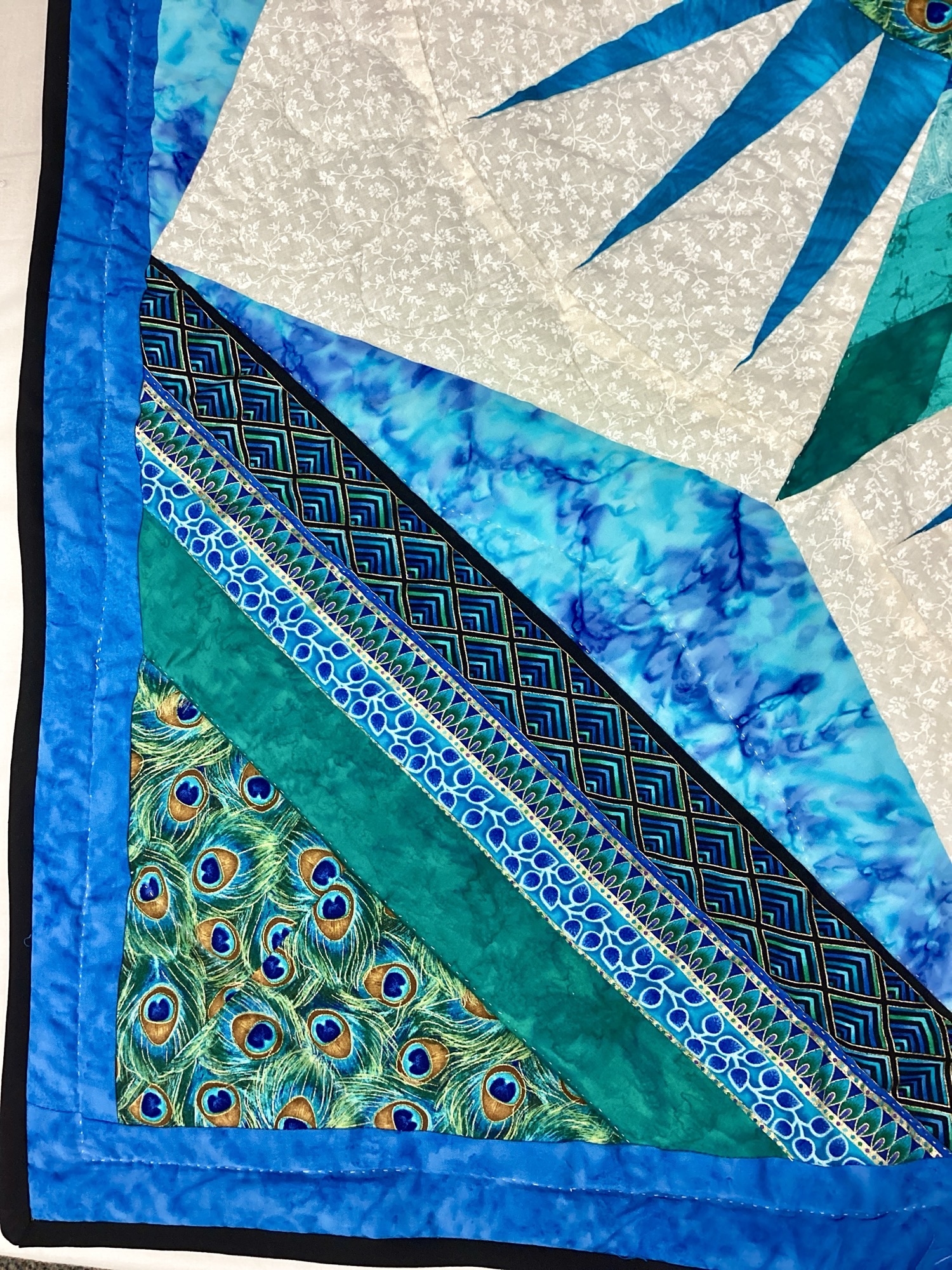 Close up of Handmade peacock wall hanging quilt with teal and sapphire blue fabrics