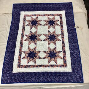 Handmade Lancaster County Americana throw quilt featuring patriotic star blocks in red white and blue with detailed hand quilting