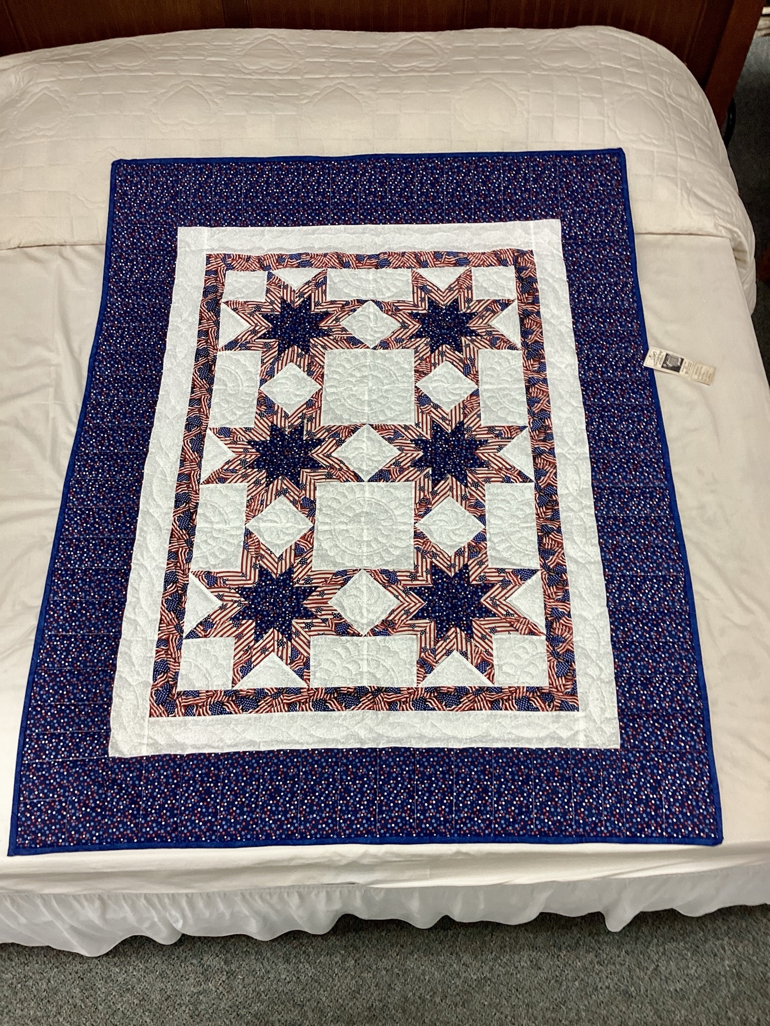 Handmade Lancaster County Americana throw quilt featuring patriotic star blocks in red white and blue with detailed hand quilting