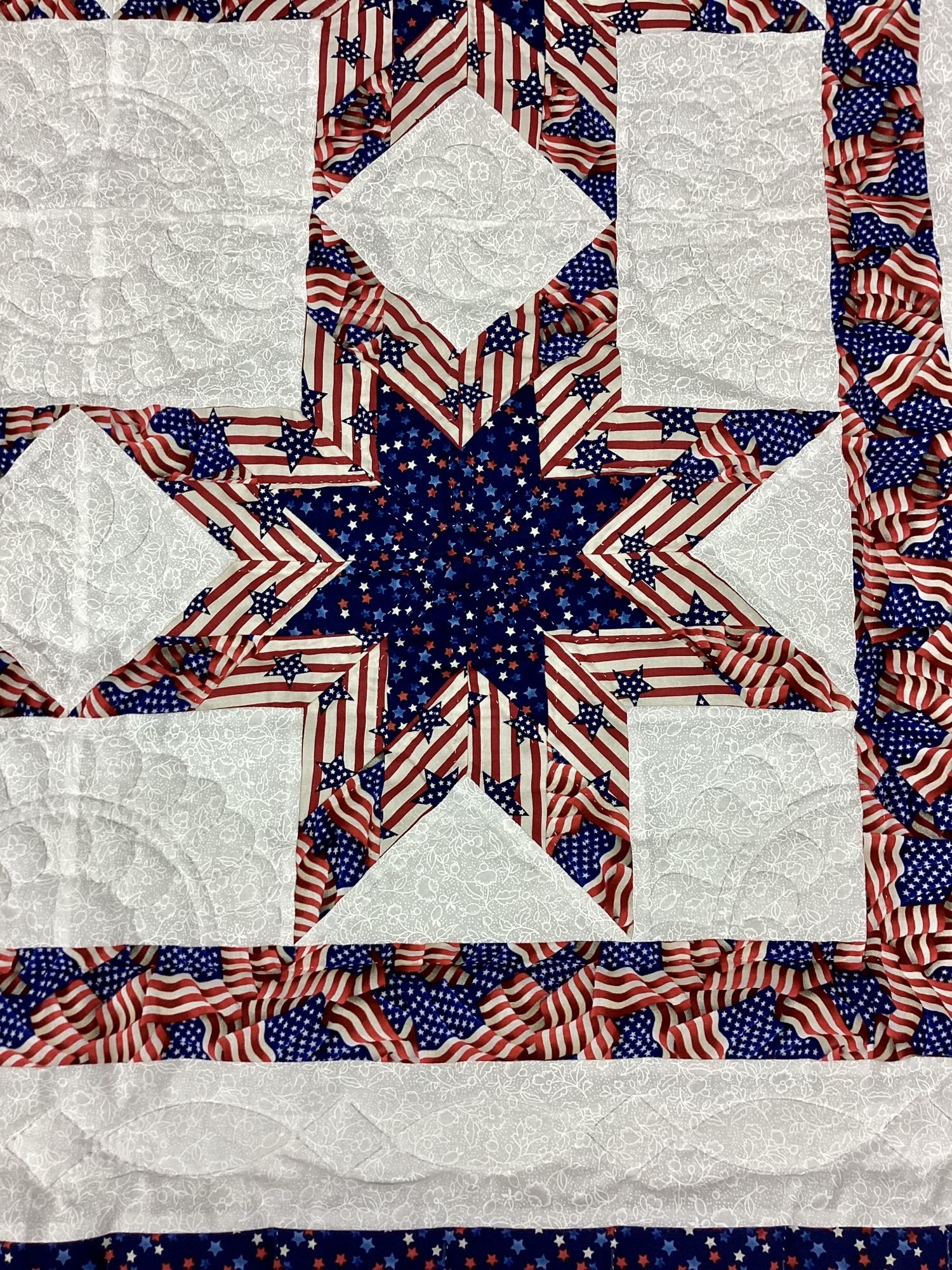 Close up of star Handmade Lancaster County Americana throw quilt featuring patriotic star blocks in red white and blue with detailed hand quilting
