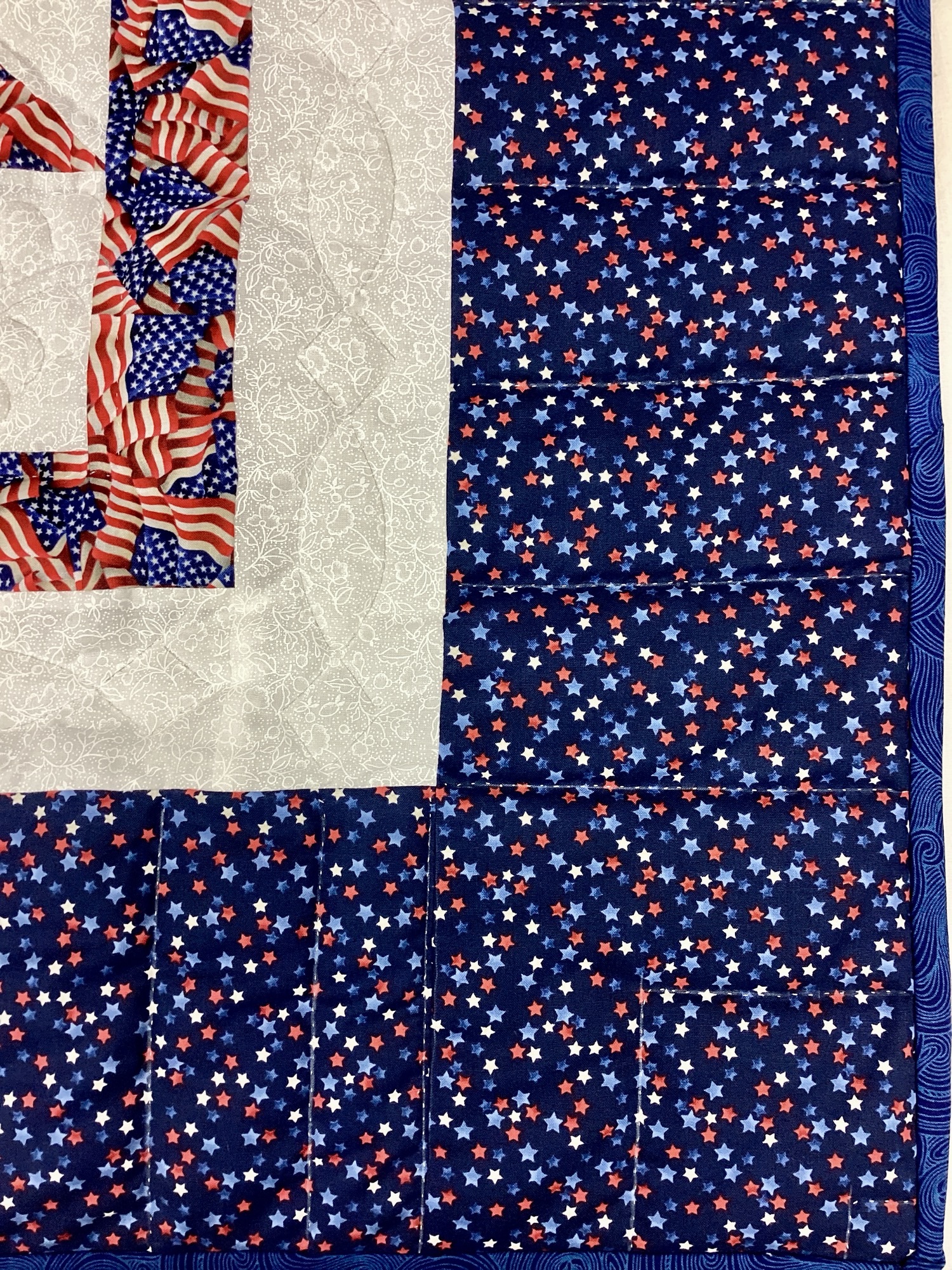 Close up of the border: Handmade Lancaster County Americana throw quilt featuring patriotic star blocks in red white and blue with detailed hand quilting