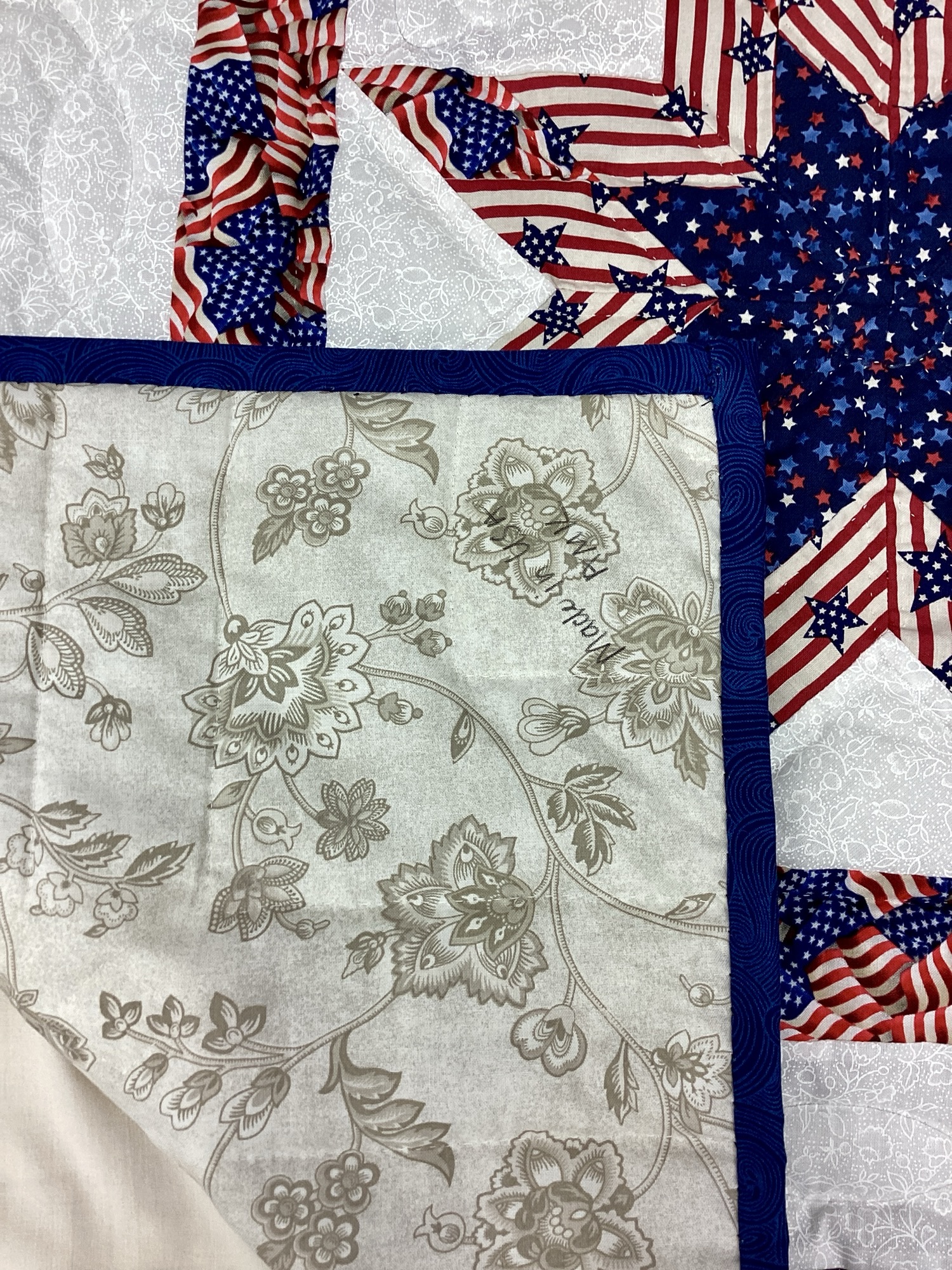 Back of Handmade Lancaster County Americana throw quilt featuring patriotic star blocks in red white and blue with detailed hand quilting
