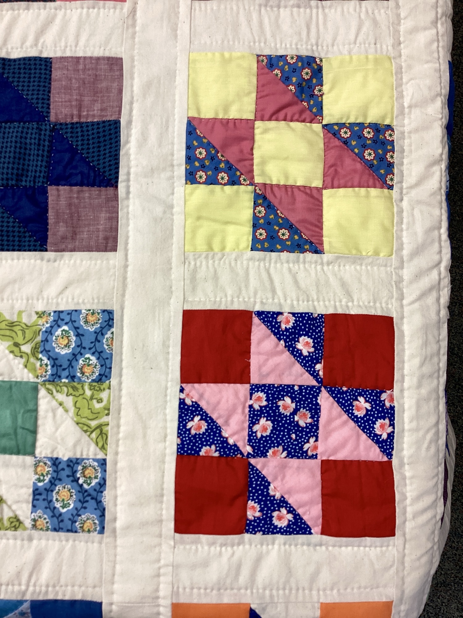 Close up of Handmade Lancaster County vintage sampler quilt using authentic 1940s fabrics with hand quilting in Twin throw size