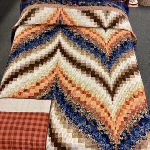 Handmade Lancaster County Bargello quilt with navy batik, rust and cream diamond wave design, navy border, and plaid backing
