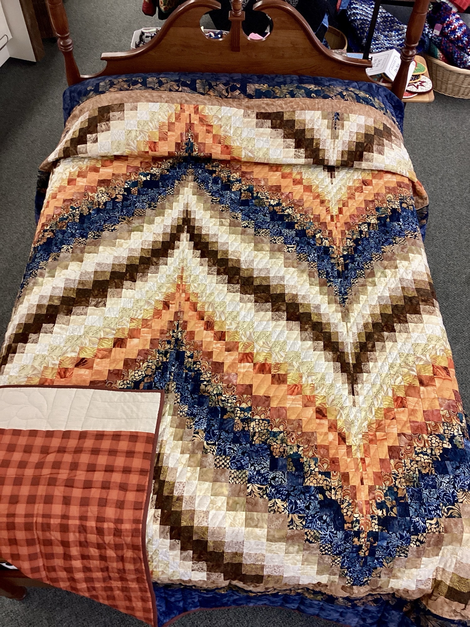 Handmade Lancaster County Bargello quilt with navy batik, rust and cream diamond wave design, navy border, and plaid backing