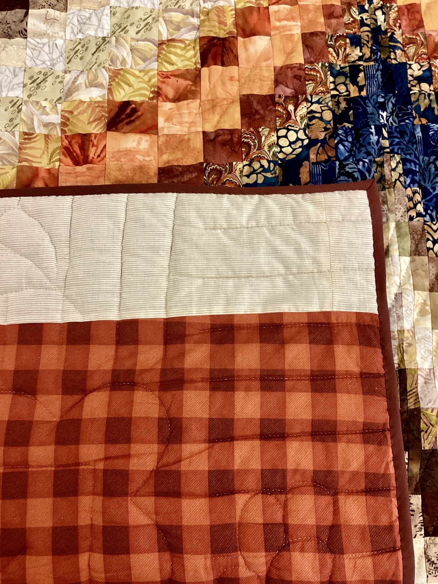 Plaid Backing on the Handmade Lancaster County Bargello quilt with navy batik, rust and cream diamond wave design, navy border.