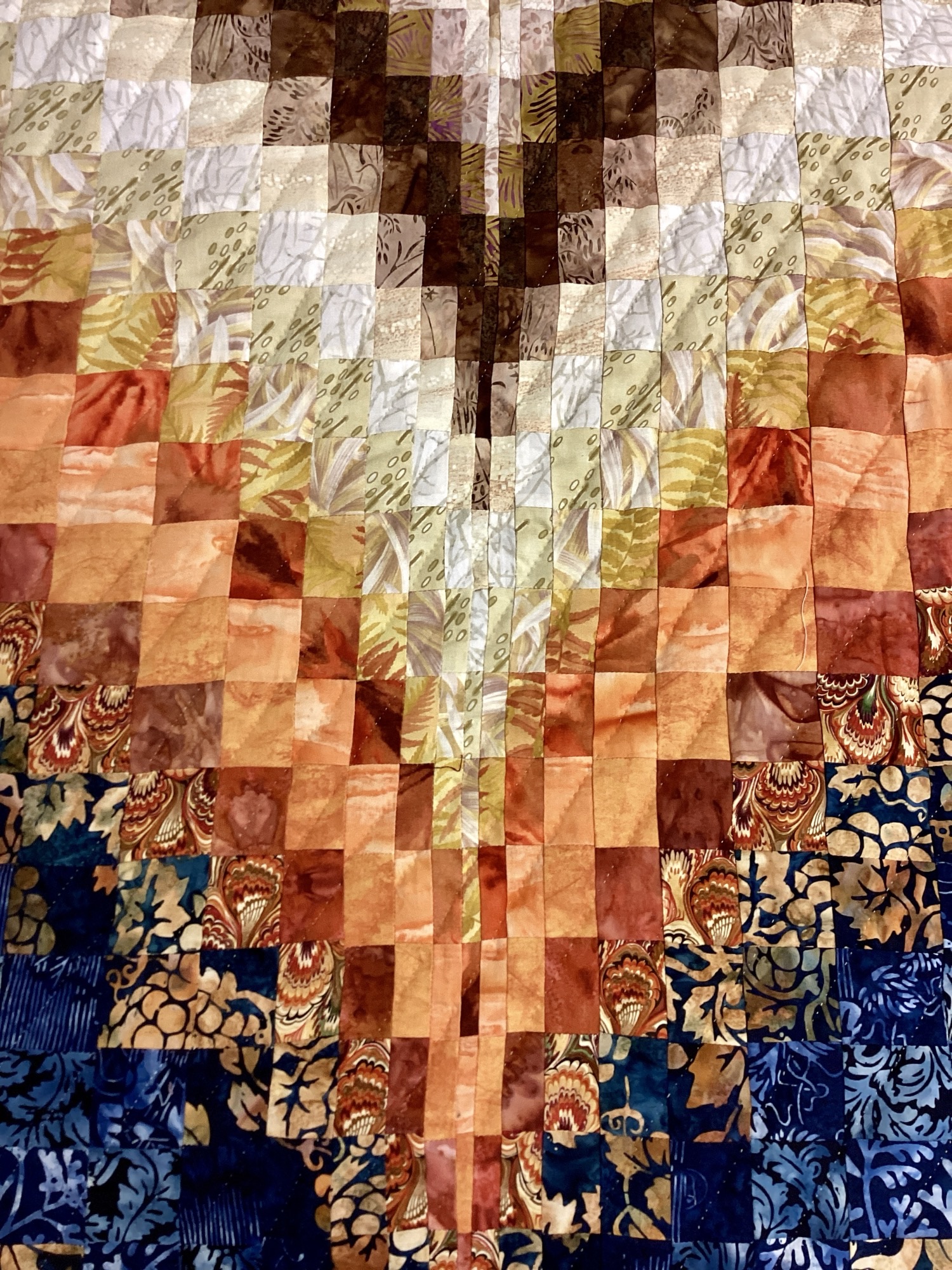 Close up: Handmade Lancaster County Bargello quilt with navy batik, rust and cream diamond wave design, navy border, and plaid backing