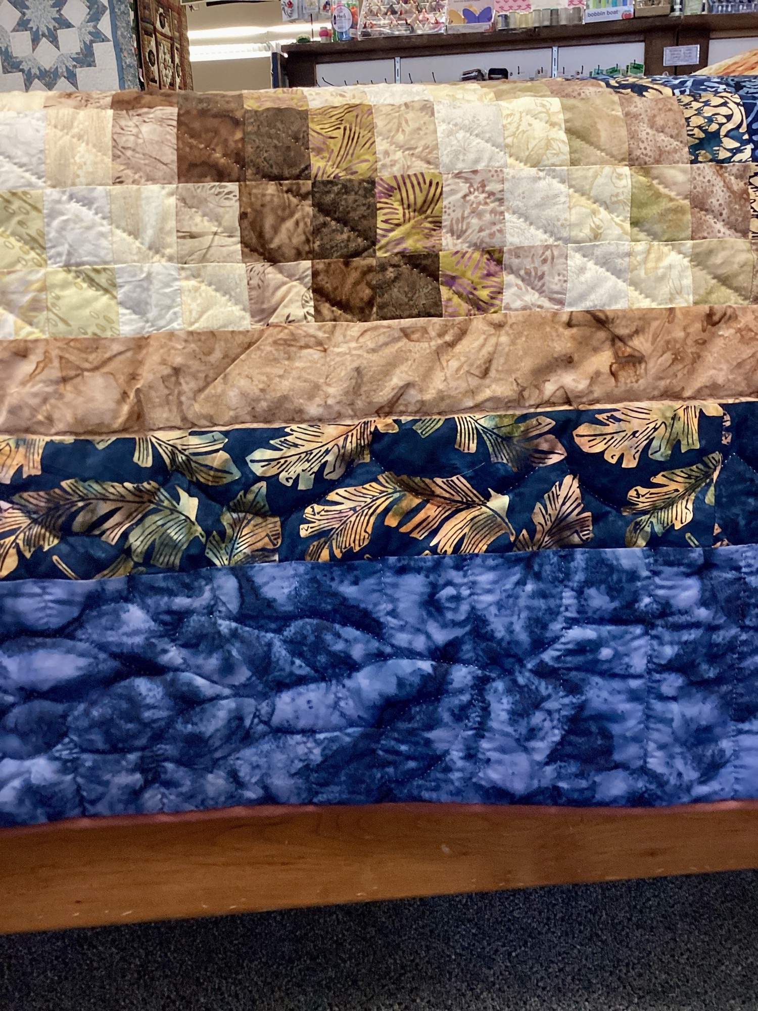 Close up: Handmade Lancaster County Bargello quilt with navy batik, rust and cream diamond wave design, navy border, and plaid backing