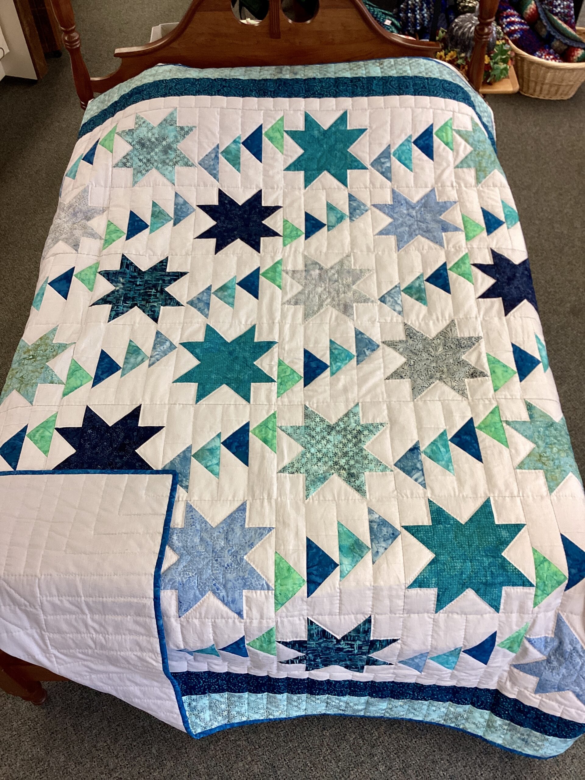 Handmade Lancaster County Flight of Geese quilt with blue and aqua star blocks, Flying Geese pattern, white background and navy border