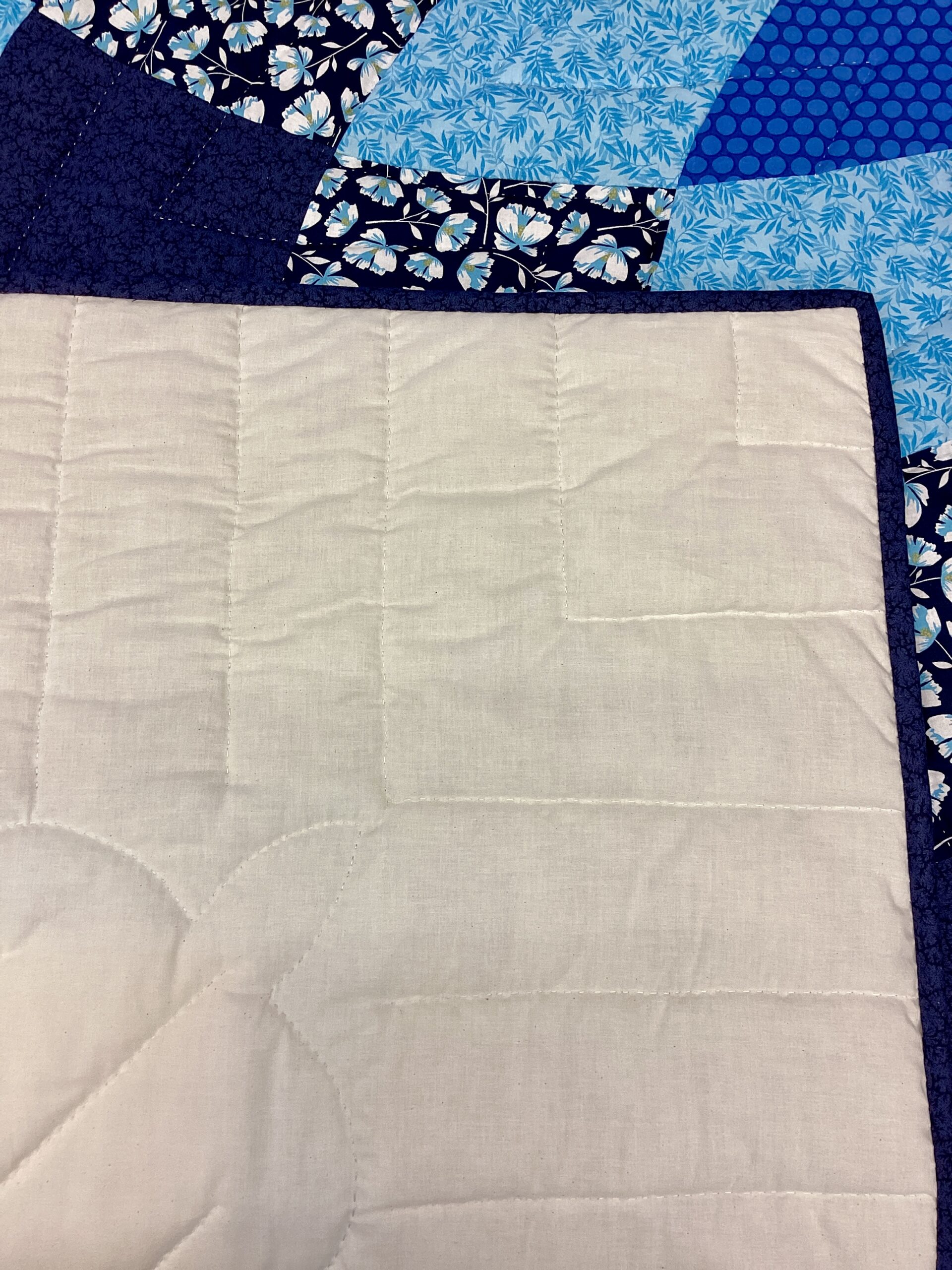 Hand quilting detail on cream background of handmade Lancaster County Amish Giant Dahlia quilt
