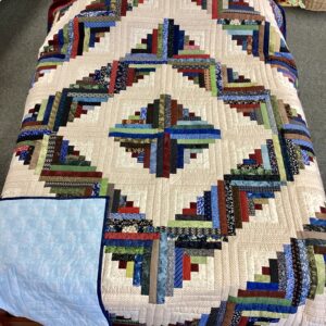 Handmade Lancaster County Amish Log Cabin quilt with colorful diamond design on cream background and navy border