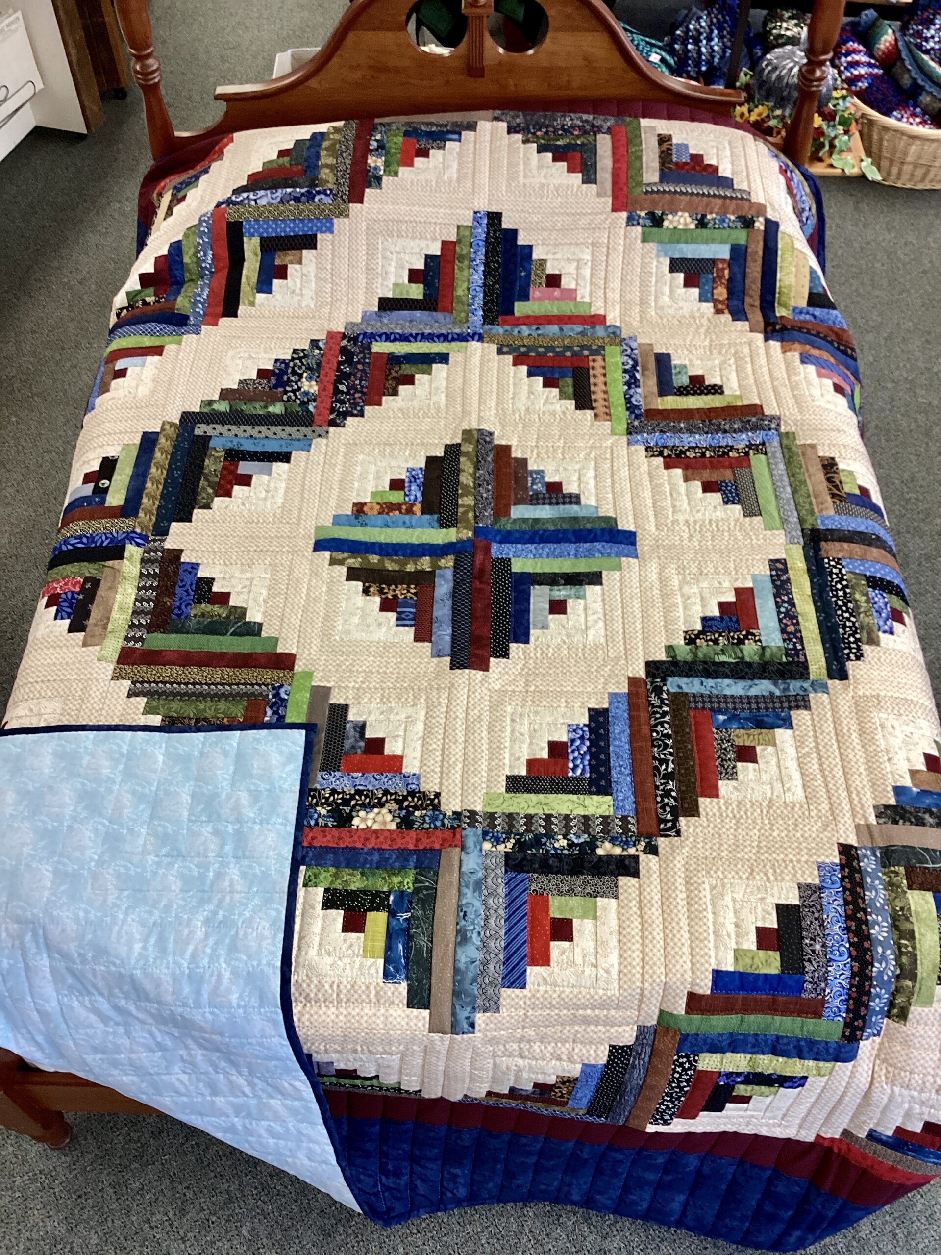 Handmade Lancaster County Amish Log Cabin quilt with colorful diamond design on cream background and navy border