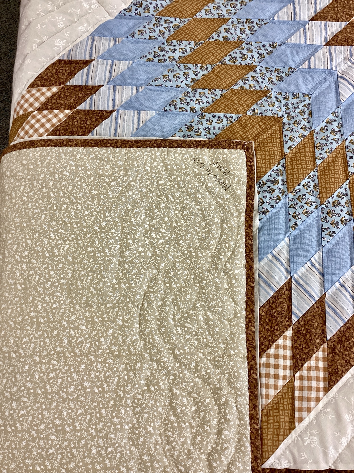 Backing on Handmade Lancaster County Amish Lone Star quilt with floating cream, sky blue and brown star design, feather quilting and floral backing