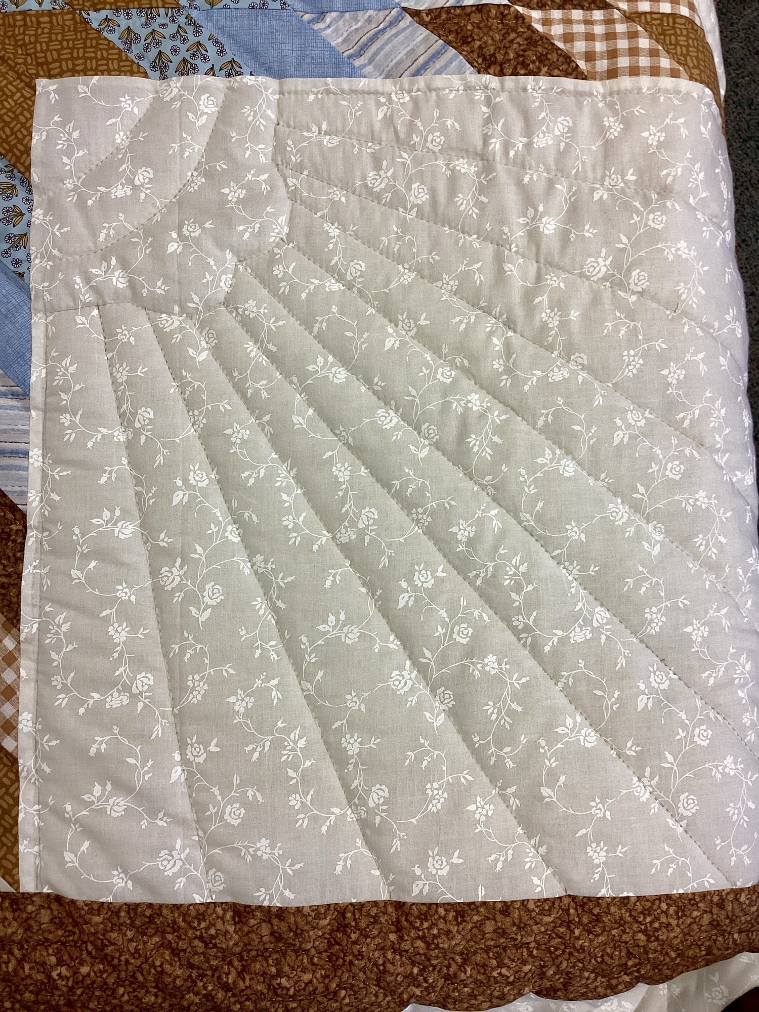 Stitching on Handmade Lancaster County Amish Lone Star quilt with floating cream, sky blue and brown star design, feather quilting and floral backing