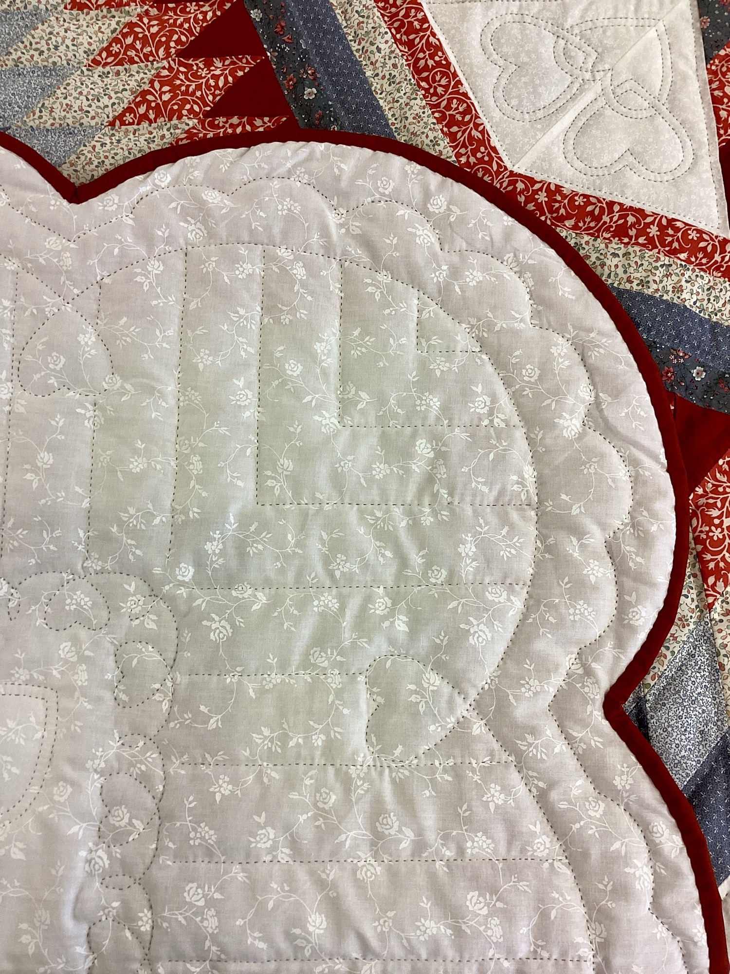 Backing of Handmade Lancaster County Amish Maryland Star quilt with red, white and gray center star, octagon border, feather quilting and scalloped edges