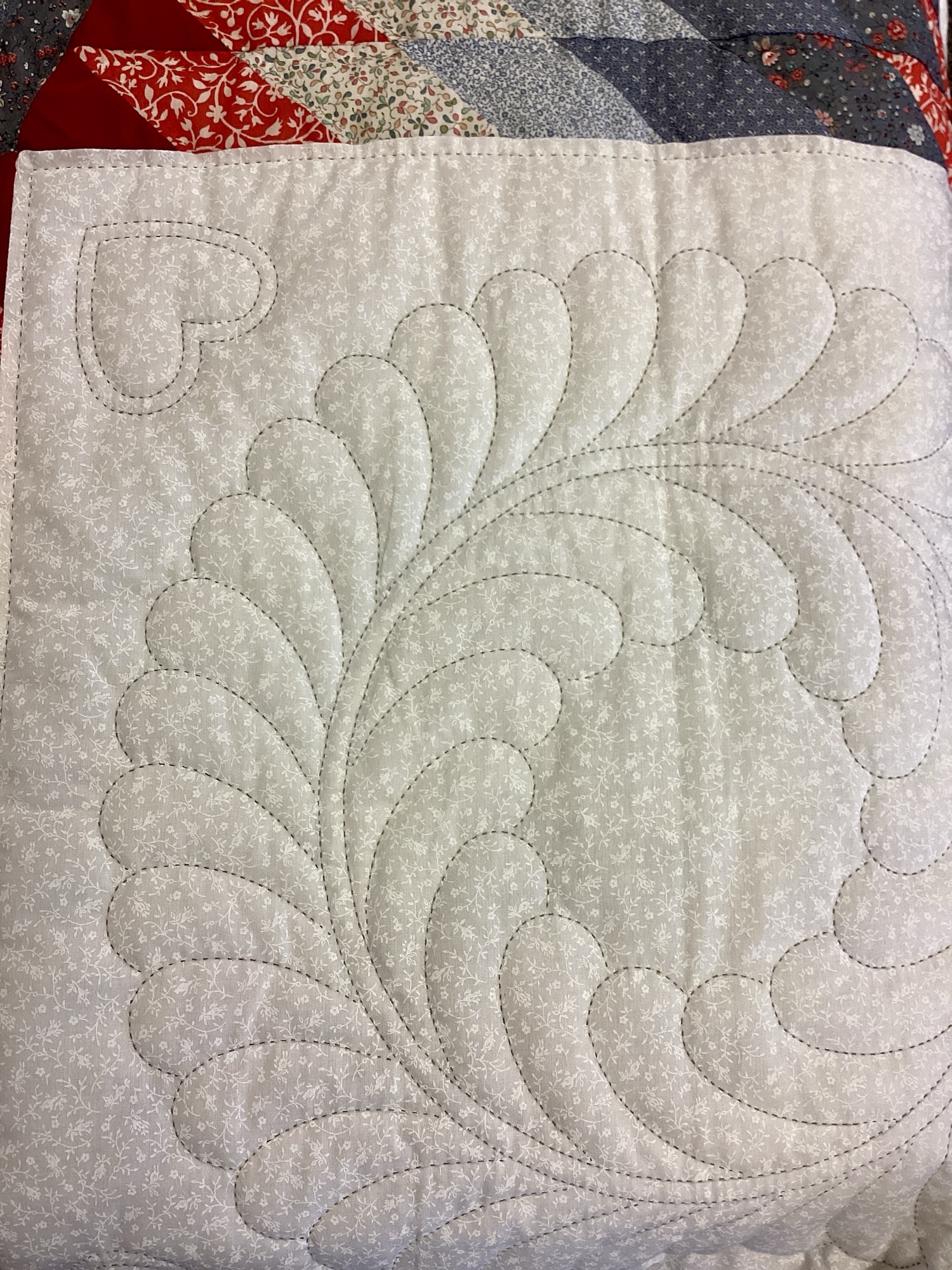 Close up of stitching on Handmade Lancaster County Amish Maryland Star quilt with red, white and gray center star, octagon border, feather quilting and scalloped edges