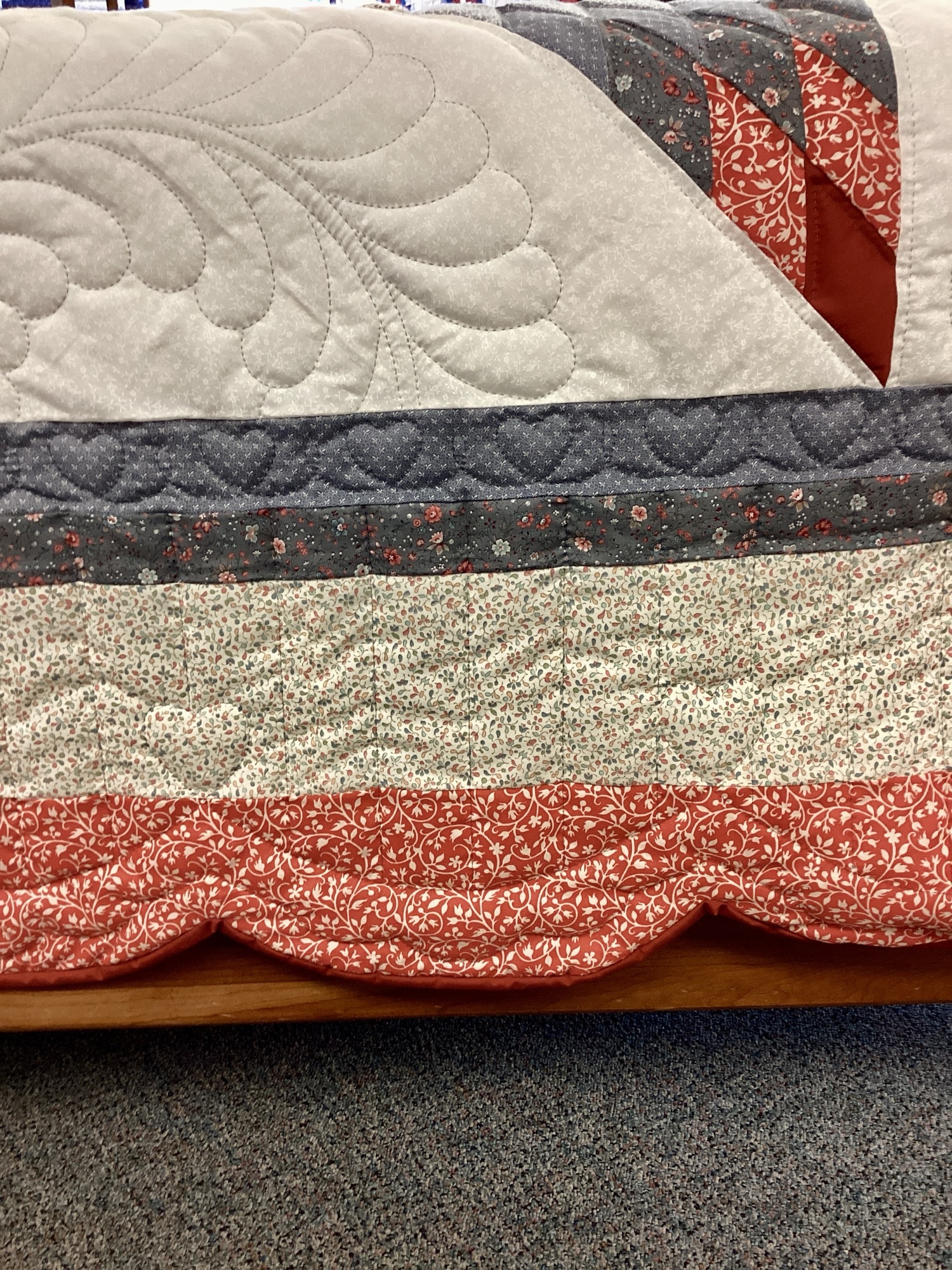 Border on Handmade Lancaster County Amish Maryland Star quilt with red, white and gray center star, octagon border, feather quilting and scalloped edges