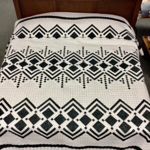 Handmade Lancaster County Mennonite Queen of Diamonds quilt with black printed geometric diamond pattern on ivory printed background and hand quilting