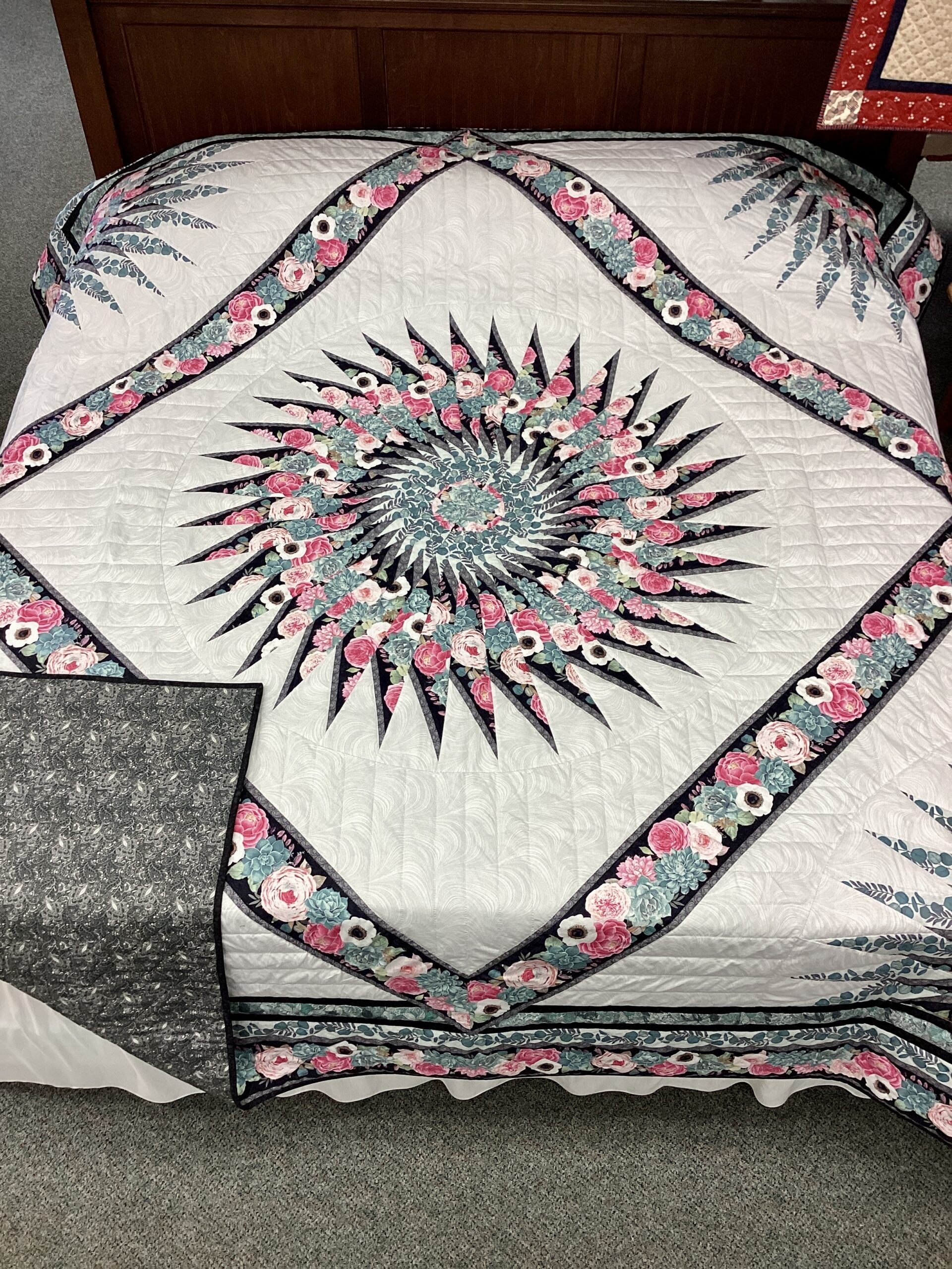 Handmade Lancaster County Amish Sawtooth Medallion quilt with floral starburst center, pink roses, aqua succulents, ivory background and black binding