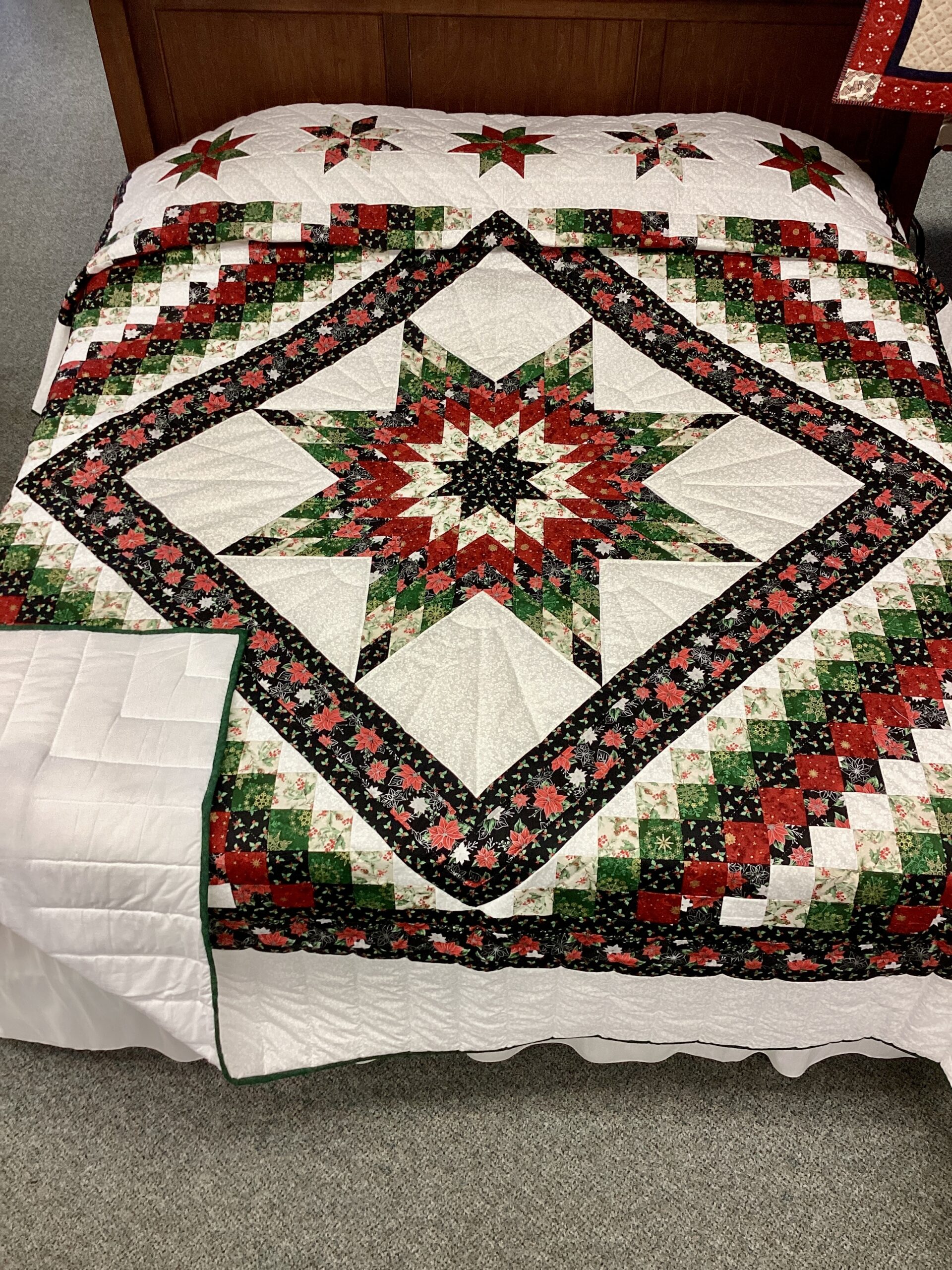 Handmade Lancaster County Mennonite Star N Common quilt with Christmas center star, poinsettia fabrics, evergreen patchwork squares and cream background
