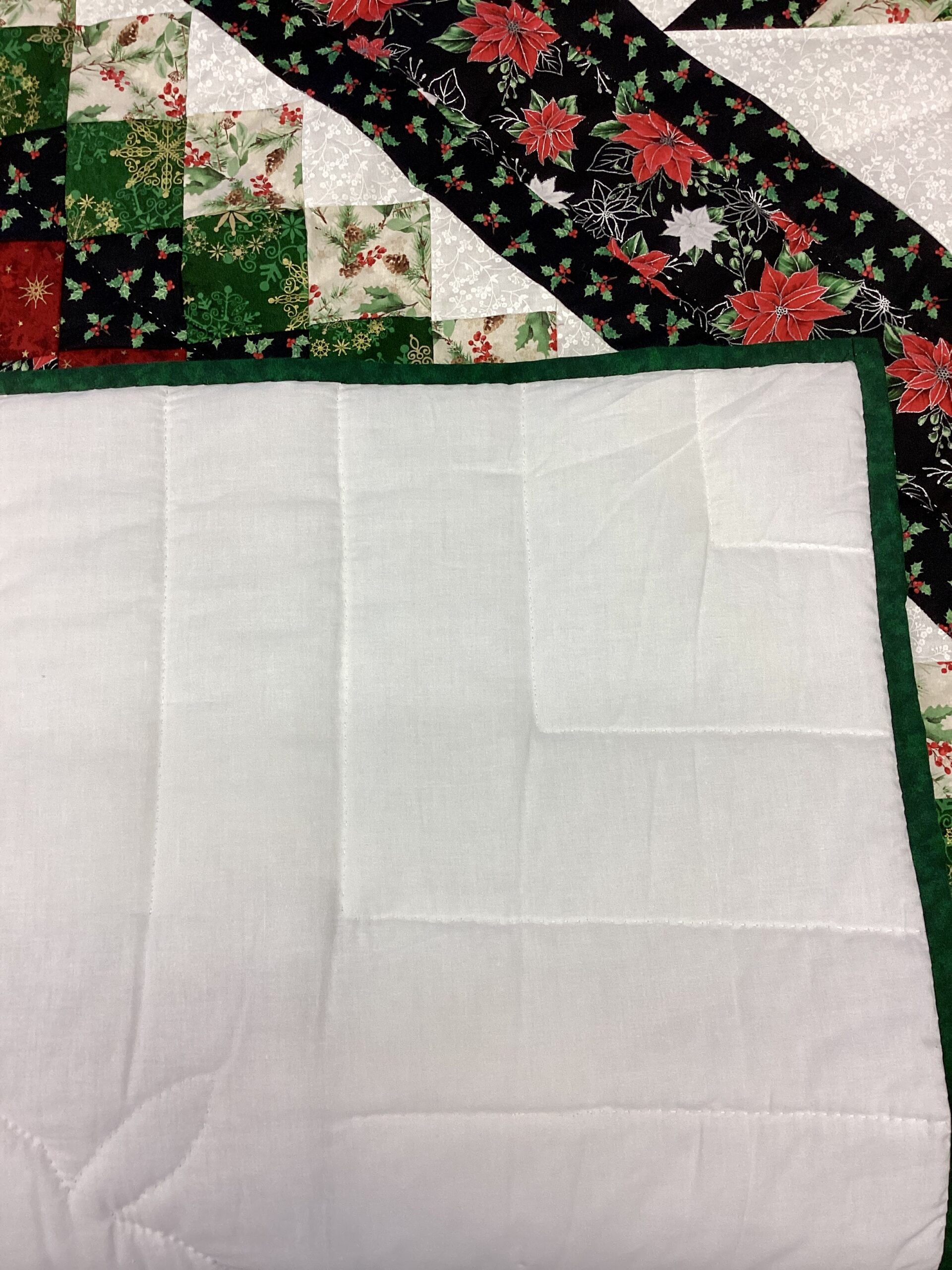 Backing of Handmade Lancaster County Mennonite Star N Common quilt with Christmas center star, poinsettia fabrics, evergreen patchwork squares and cream background