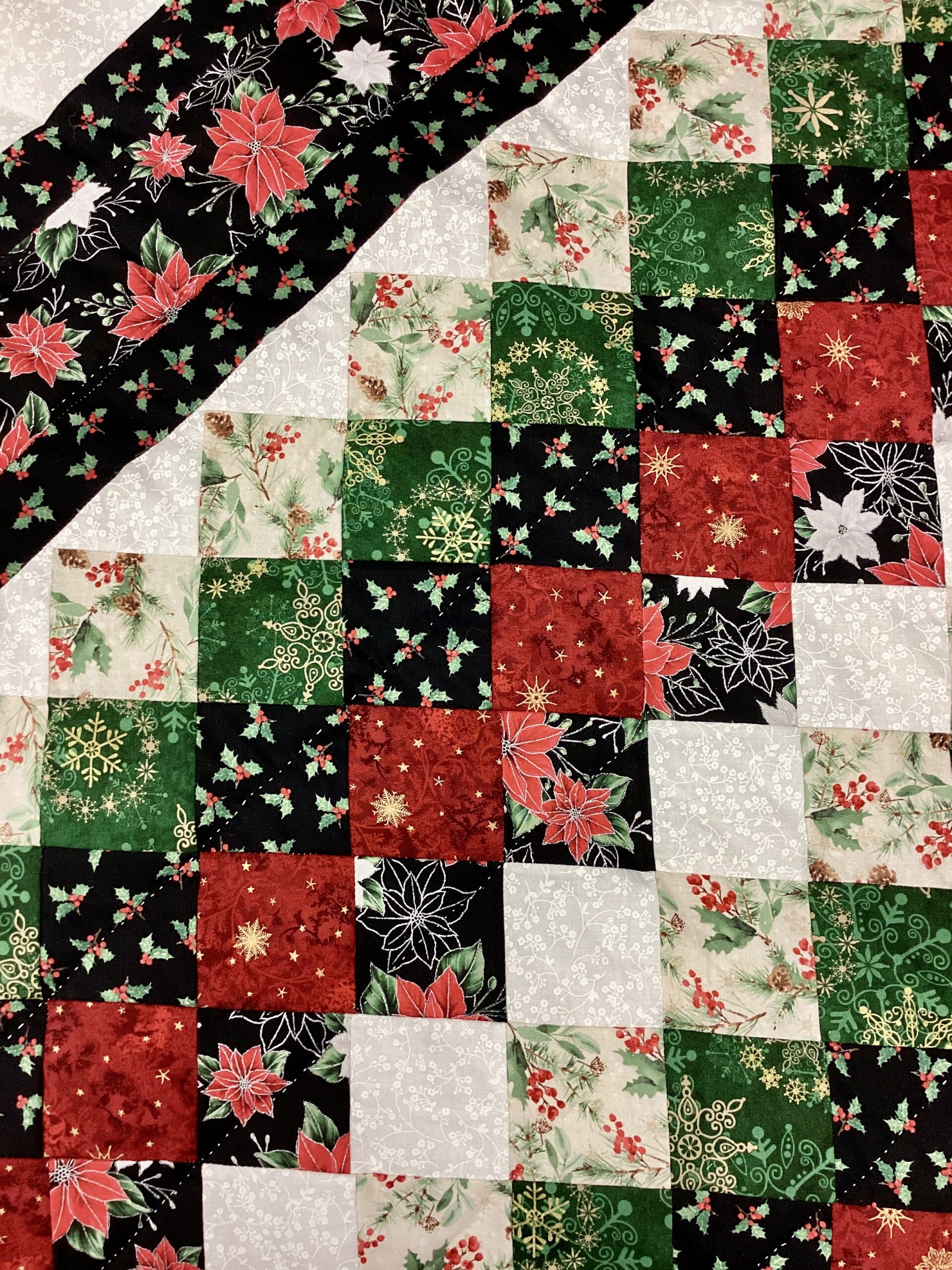 up close of Handmade Lancaster County Mennonite Star N Common quilt with Christmas center star, poinsettia fabrics, evergreen patchwork squares and cream background