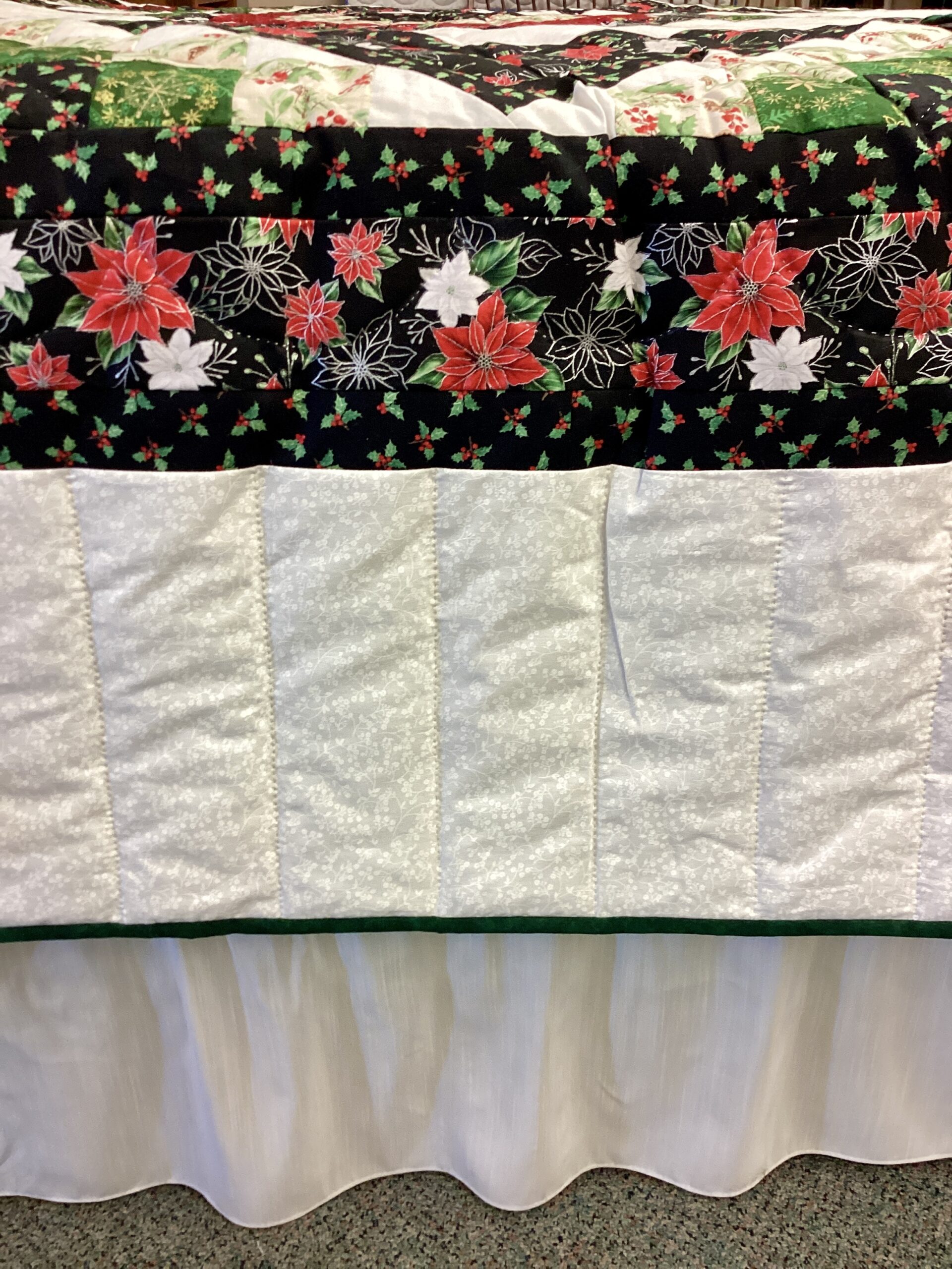up close of Handmade Lancaster County Mennonite Star N Common quilt with Christmas center star, poinsettia fabrics, evergreen patchwork squares and cream background