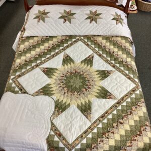 Handmade Lancaster County Star N Common quilt with green and cream center star, floral fabrics, scalloped edges, and hand-quilted white background