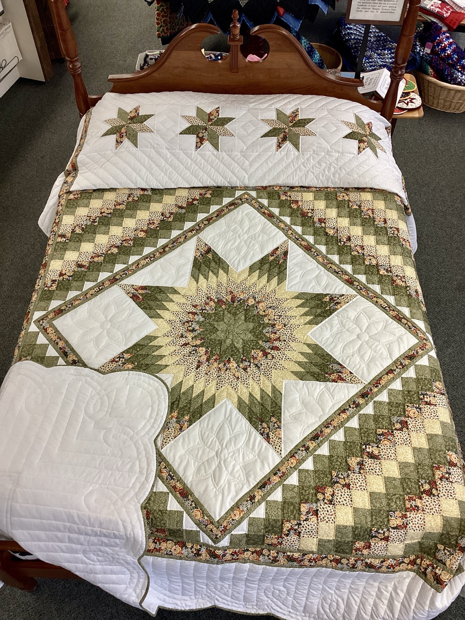 Handmade Lancaster County Star N Common quilt with green and cream center star, floral fabrics, scalloped edges, and hand-quilted white background