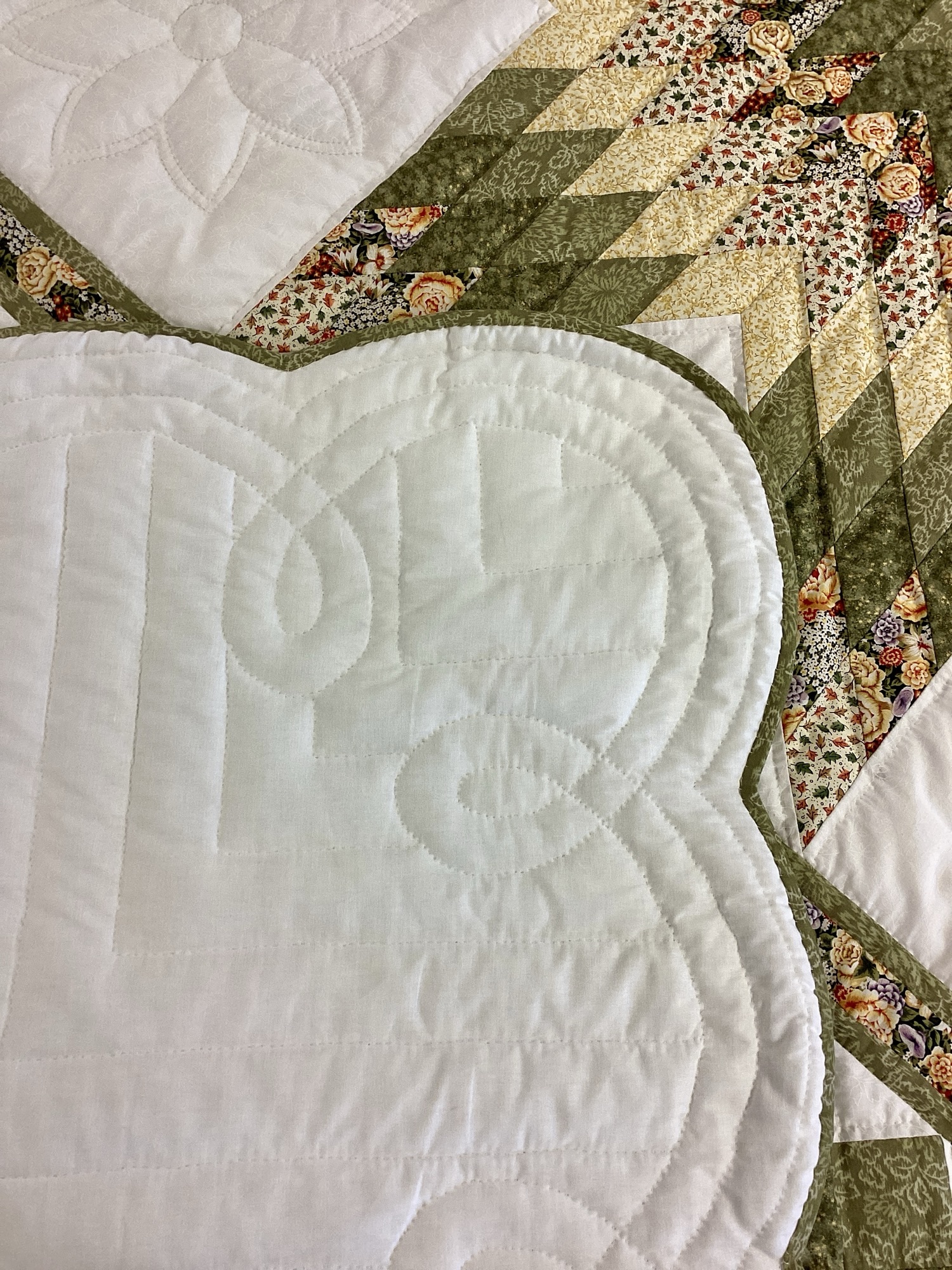 Close-up of scalloped edge on Star N Common quilt showing hand quilting, green binding, and floral star fabrics