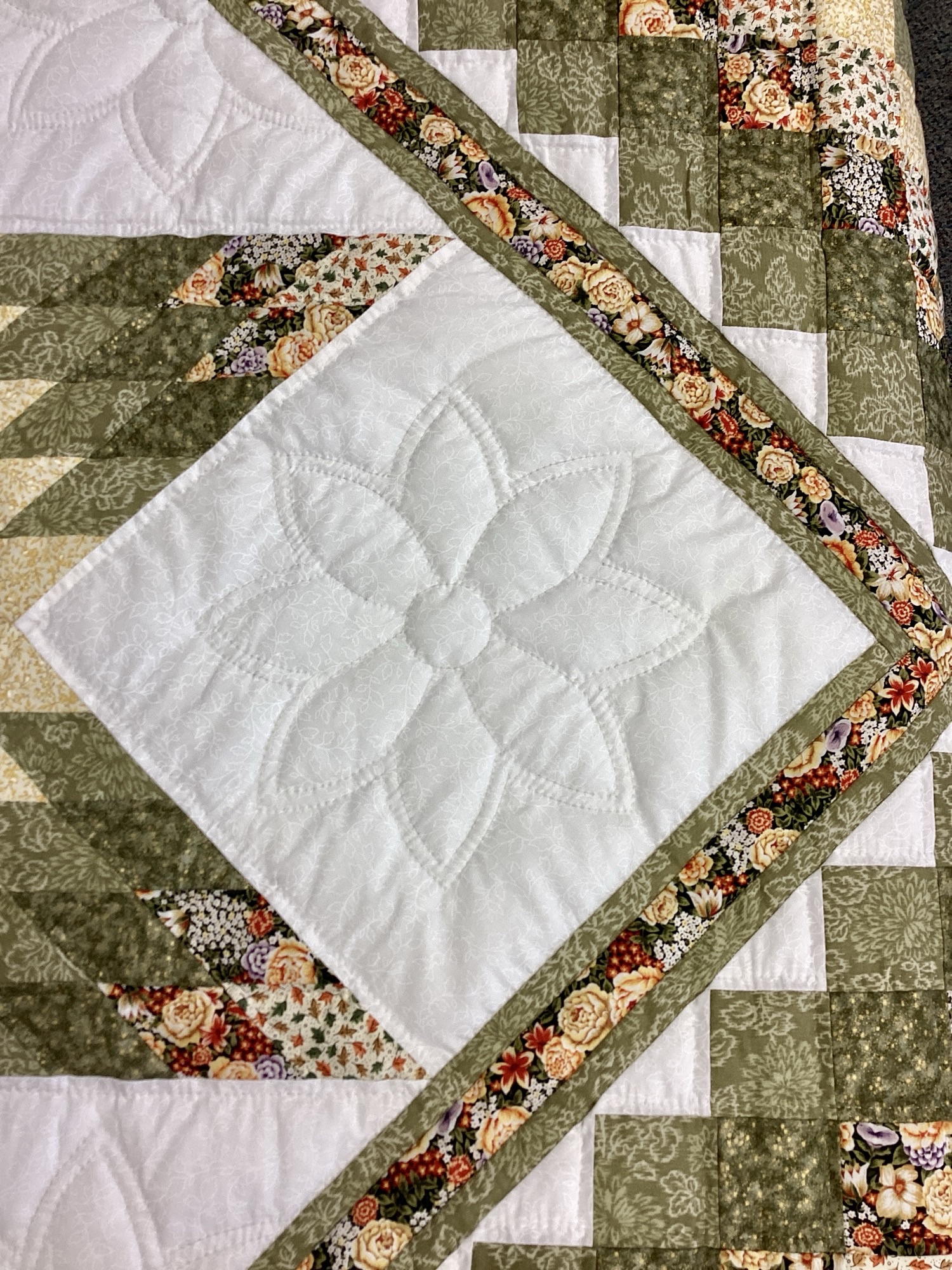 Detailed view of Star N Common quilt center featuring green and cream Lone Star design with floral fabrics and hand quilting
