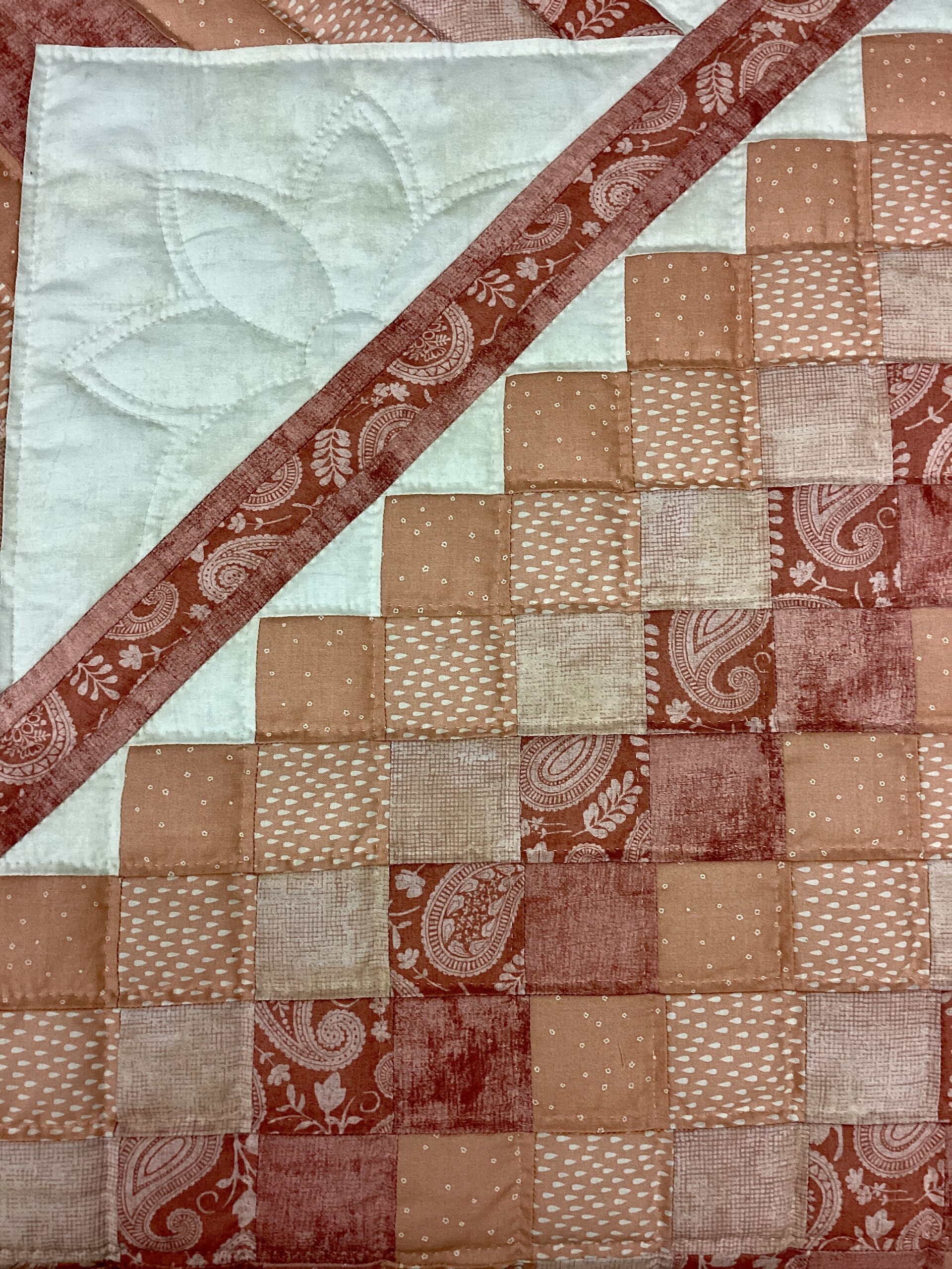Close-up of blush peach Star N Common center star with intricate hand quilting and cream setting blocks