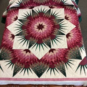 Handmade Lancaster County Mennonite Star of Beauty quilt with burgundy and pink floral starburst design, cream background, green accents and scalloped border