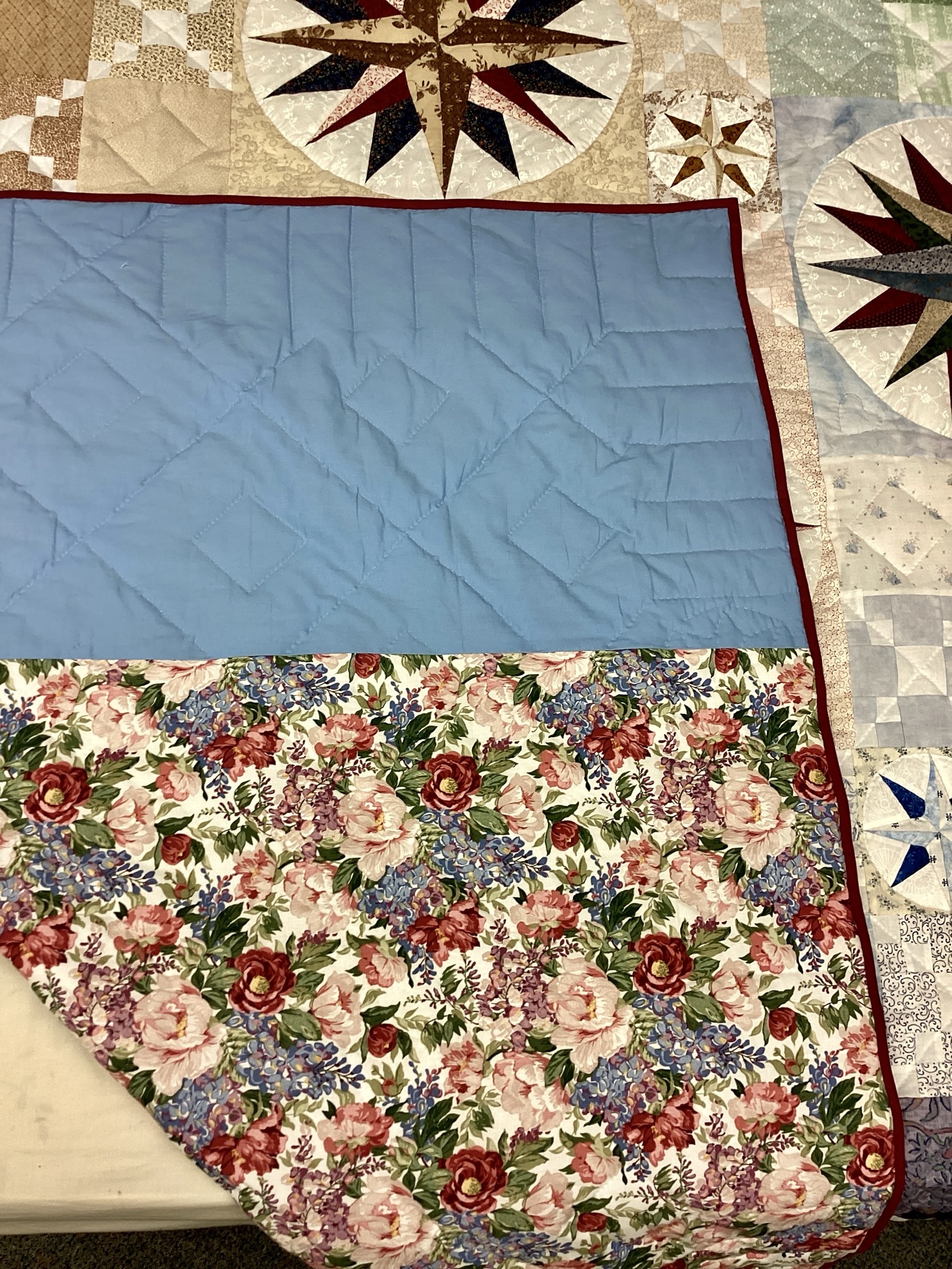 Blue and floral backing fabric on handmade Susquehanna Compass Mennonite quilt with navy binding